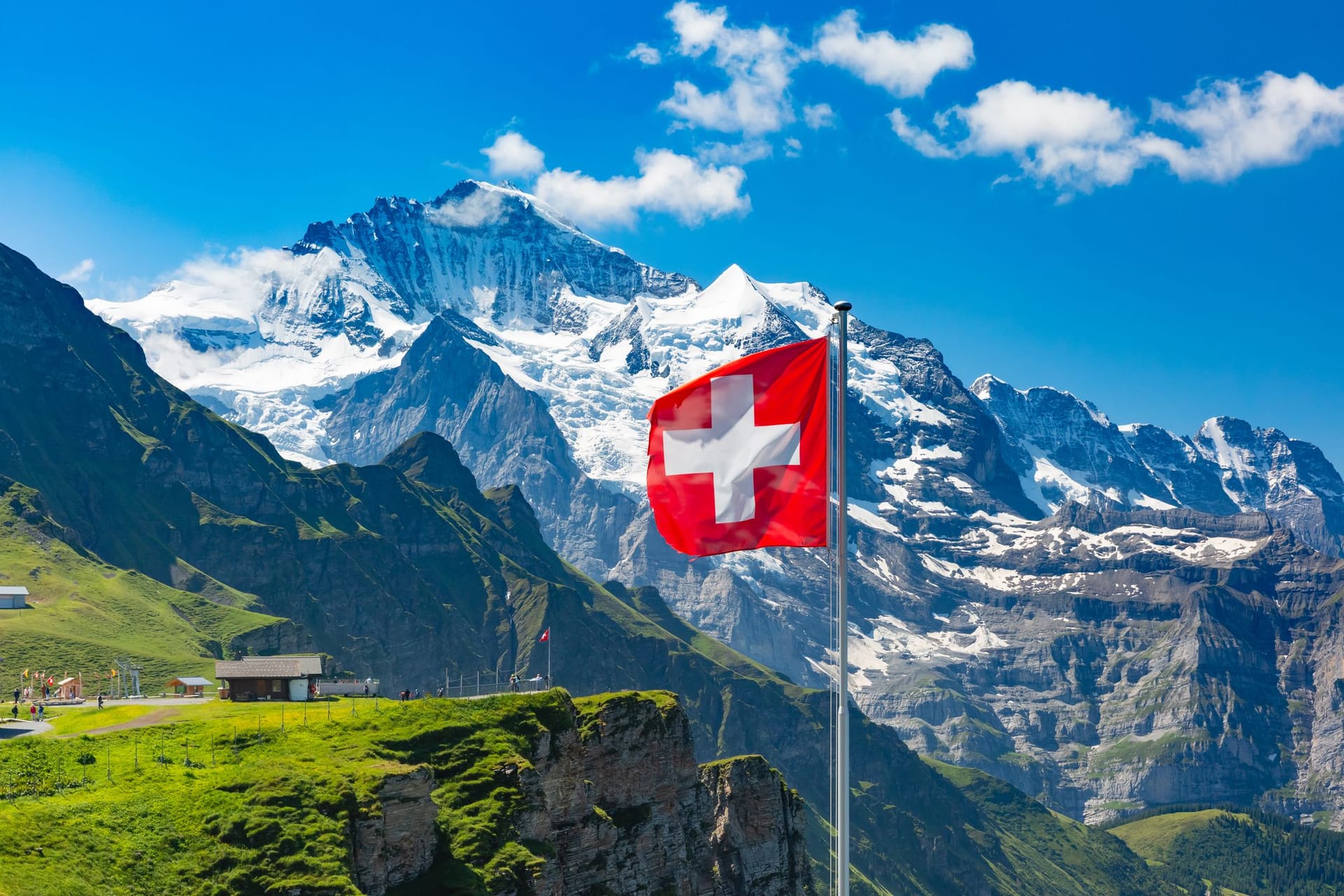 Schweizer Berge im Sommer bei strahlendem Sonnenschein mit wehender Schweizer Nationalflagge