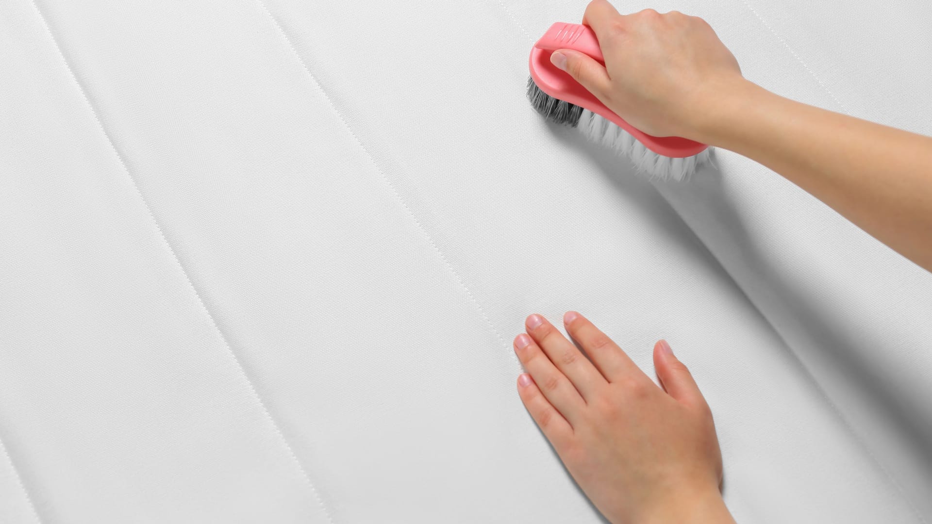 Woman cleaning white mattress with brush, closeup. Space for text