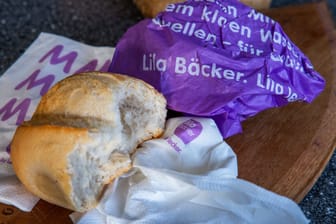Eine zerknüllte Brottüte von Lila Bäcker neben einem Brötchen (Symbolbild): Dem Unternehmen sei es nicht gelungen, die Logistik in seinem großen Einzugsgebiet gut zu organisieren.