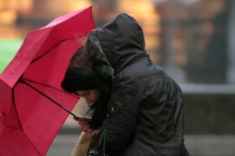 Passantin kämpft während eines starken Regenschauers mit Sturmböen mit ihrem Regenschirm (Symbolbild): Zum Wochenende wird es deutlich kühler und es kann schneien.