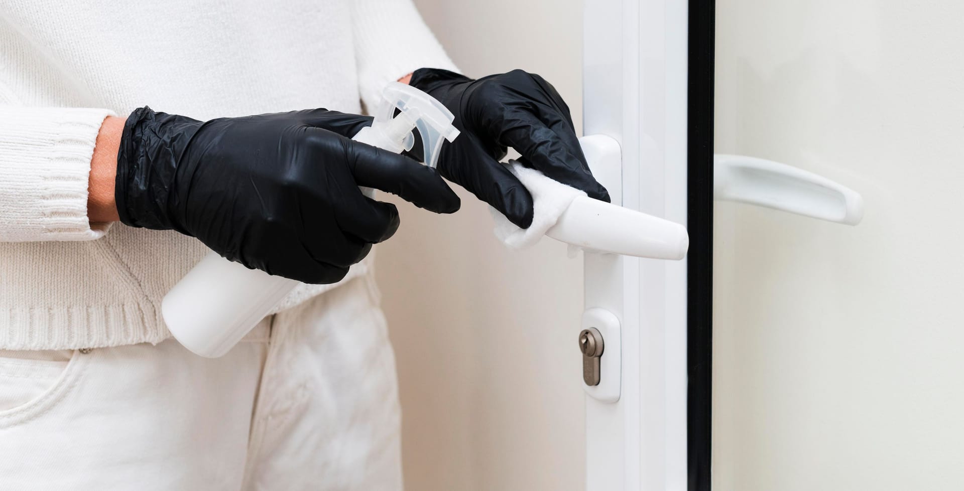 hands with gloves disinfecting door handle