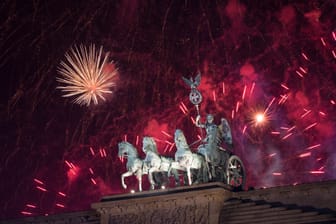 Das Feuerwerk zum Jahreswechsel steigt hinter dem Brandenburger Tor auf.