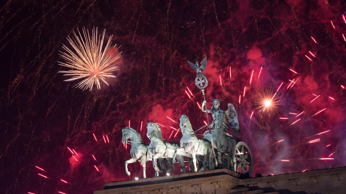 Das Feuerwerk zum Jahreswechsel steigt hinter dem Brandenburger Tor auf.