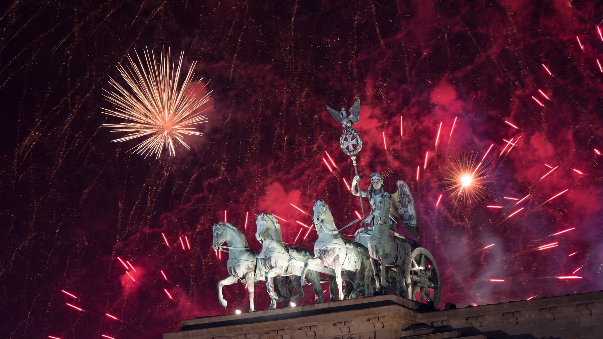 Das Feuerwerk zum Jahreswechsel steigt hinter dem Brandenburger Tor auf.