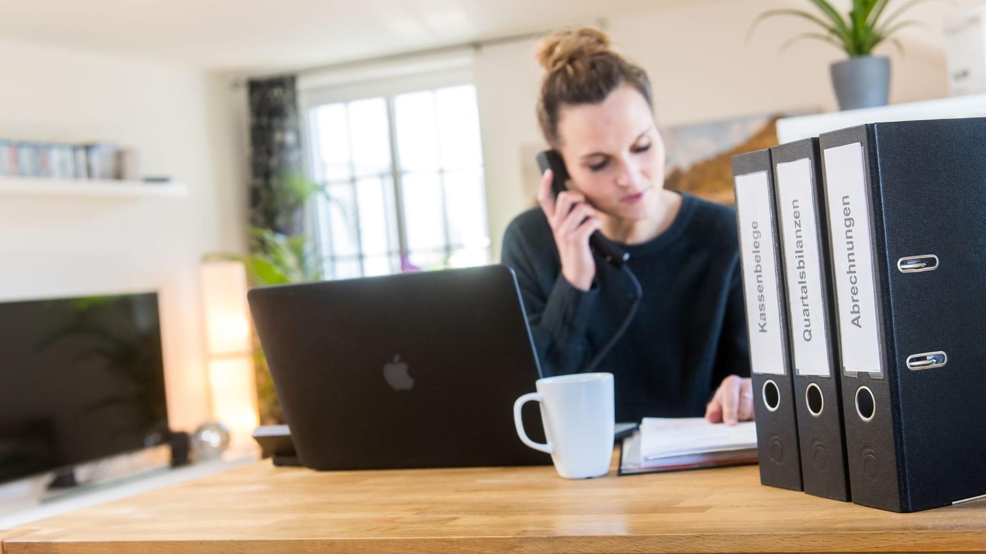 Person sitzt am Schriebtisch und telefoniert Person sitzt am Schriebtisch und telefoniert
