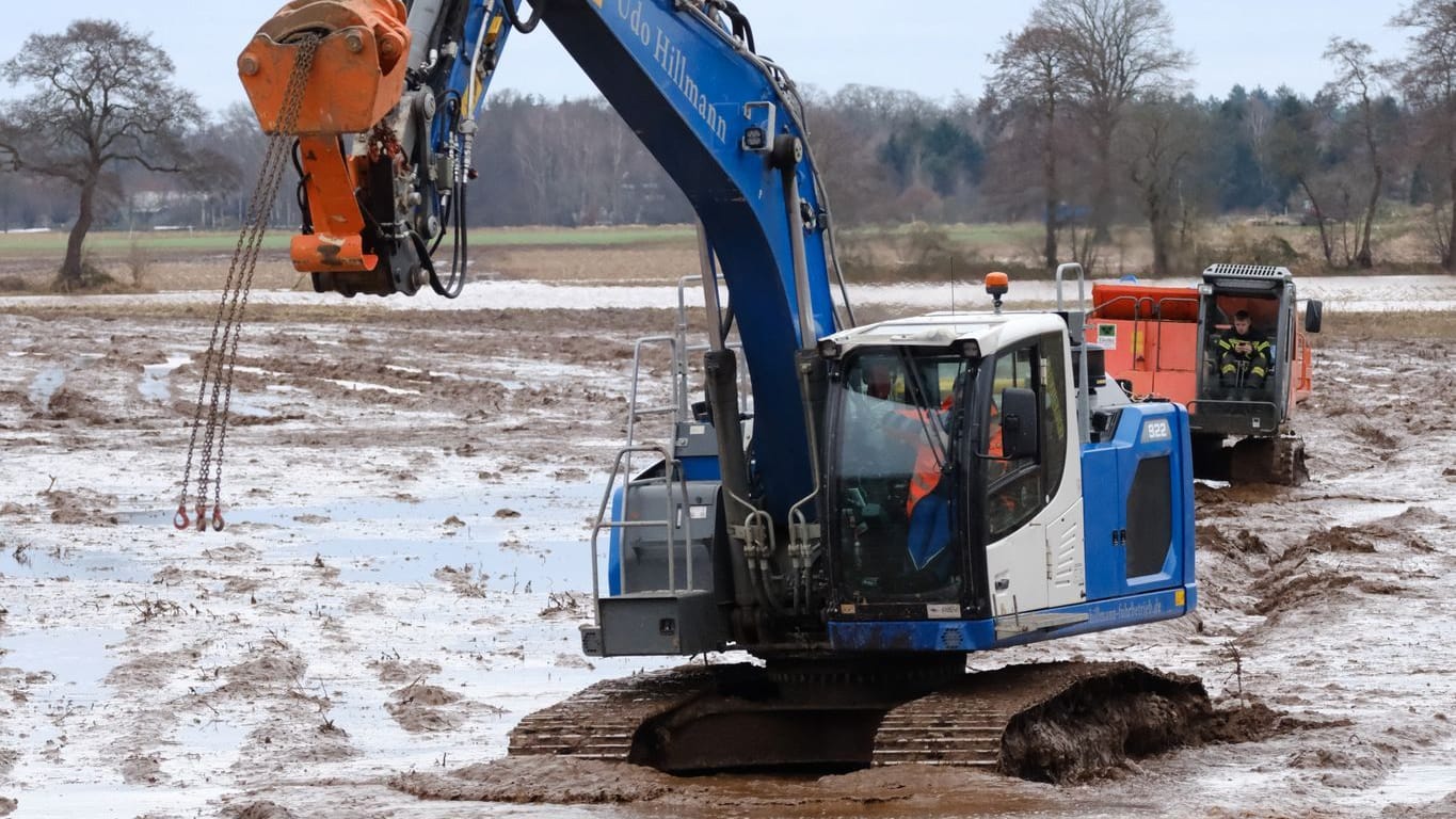 Ein Bagger fährt über einen aufgeweichten Acker bei Sandkrug südlich von Oldenburg. An der Hunte und Wümme gibt es seit Tagen keine Entwarnung.