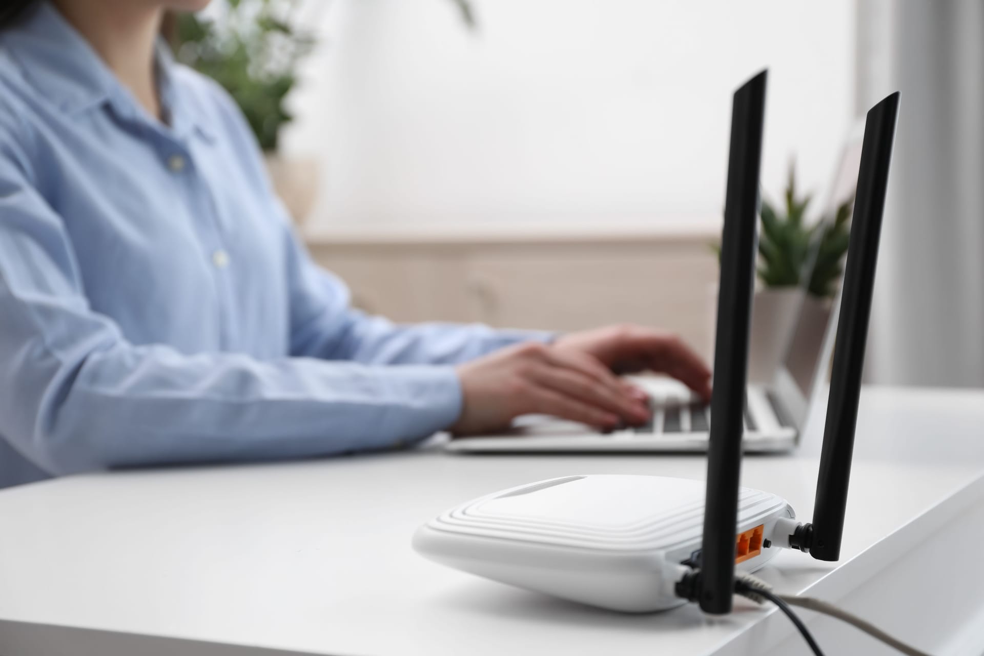 Woman working in office, focus on connected with cable router. Wireless internet communication