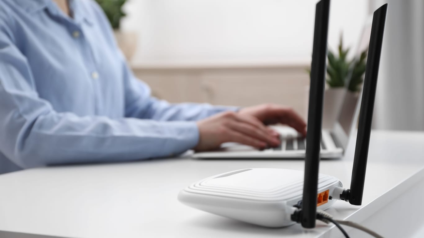 Woman working in office, focus on connected with cable router. Wireless internet communication