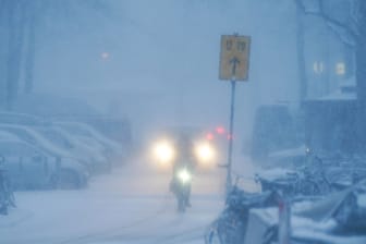 Ein Fahrradfahrer fährt auf einer verschneiten Straße (Symbolbild): In Bayern fällt an mehreren Schulen der Unterricht aus.