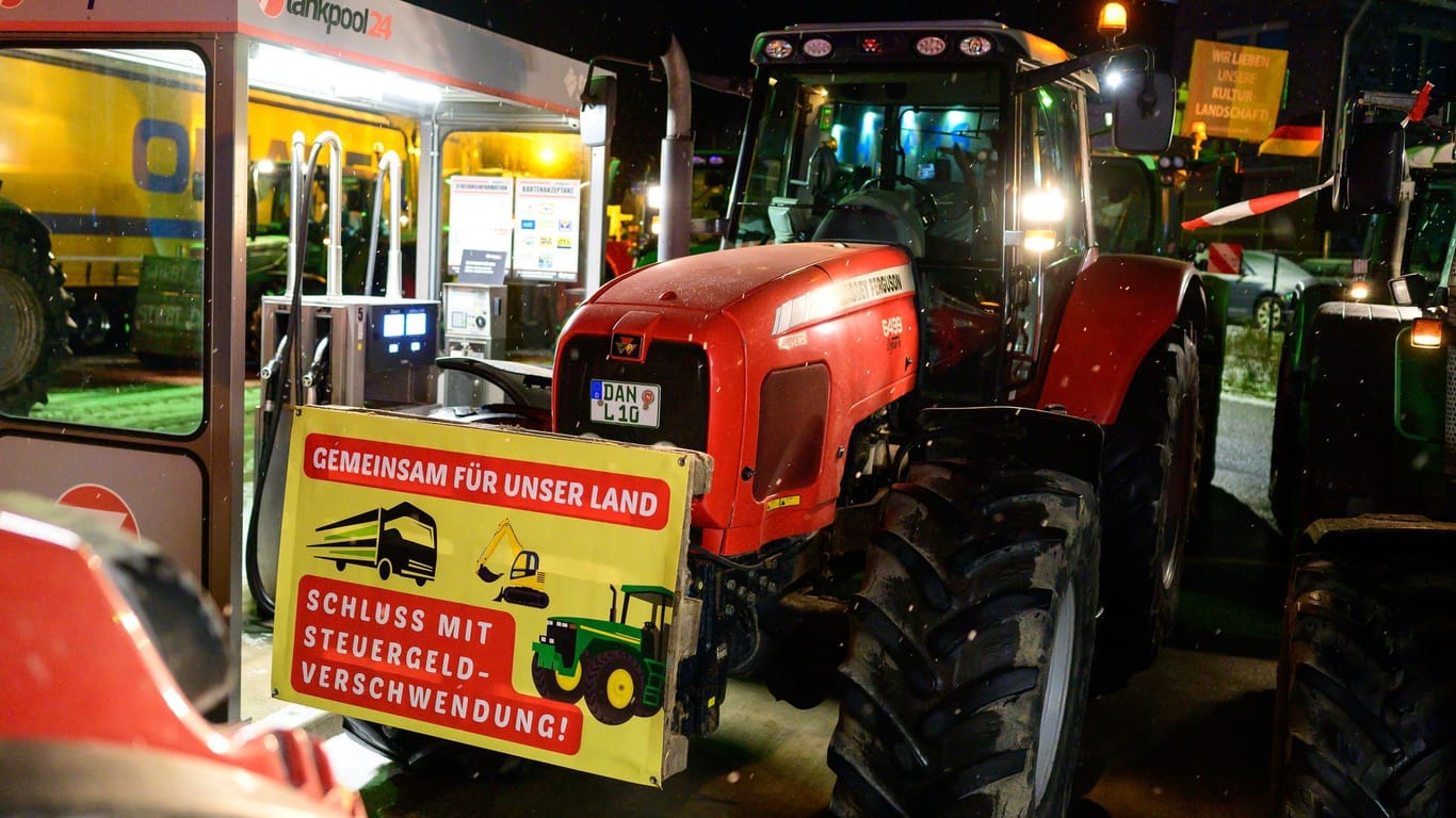 Traktor mit Transparent an einer Zapfsäule: Bereits seit der Nacht sind zahlreiche Landwirte mit ihren Gefährten auf den Straßen unterwegs.