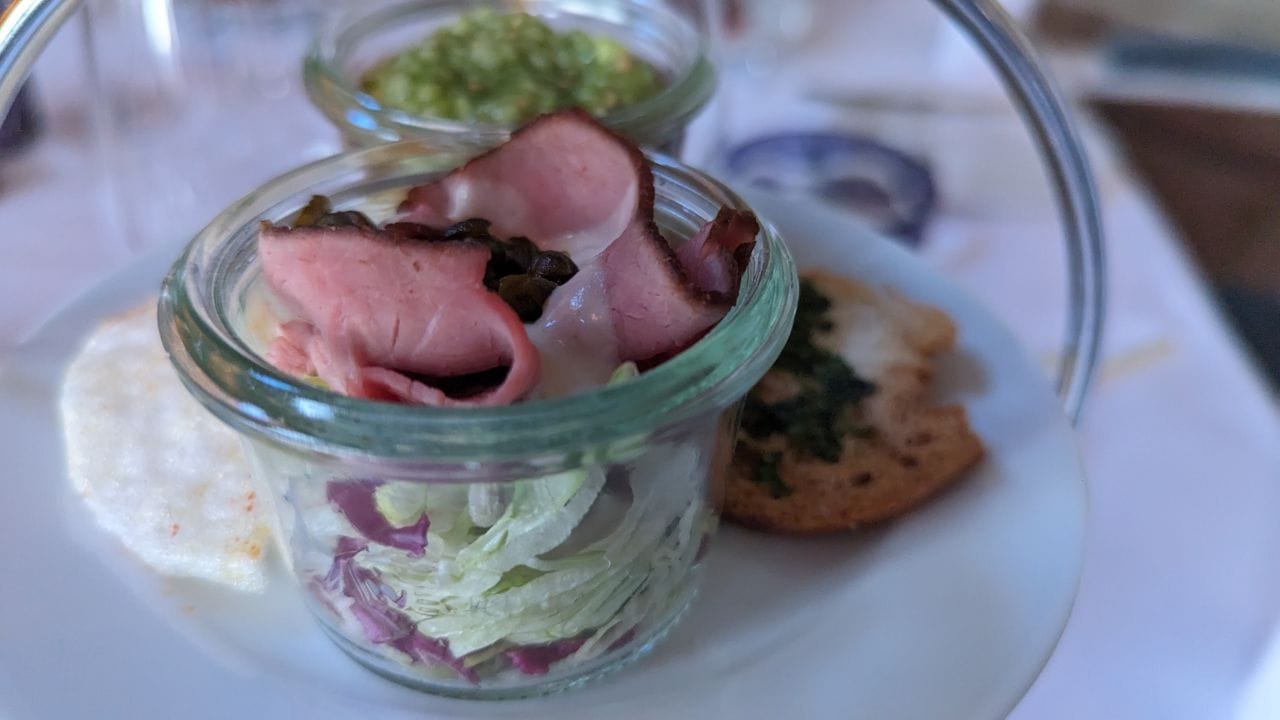 Vorspeise für die Gäste am Tisch: Rosa gegarter Tafelspitz, serviert mit Crackern und einer Garnelen-Sülze auf einem Bett aus Kokos-Garnelengras-Mousse.