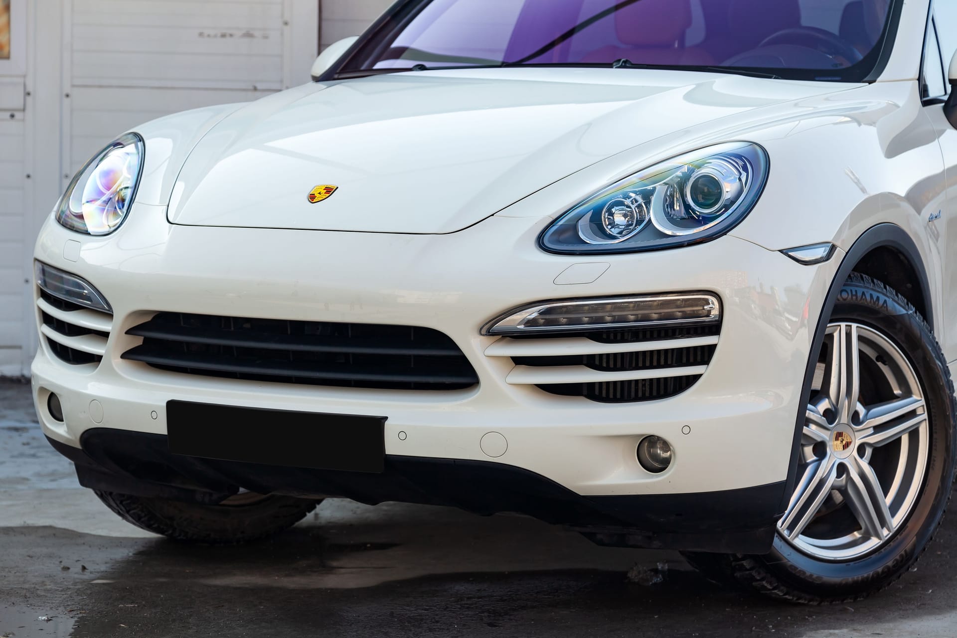 White Porsche Cayenne 958 2011 year front view in excellent condition in a parking space among other cars at sunny day