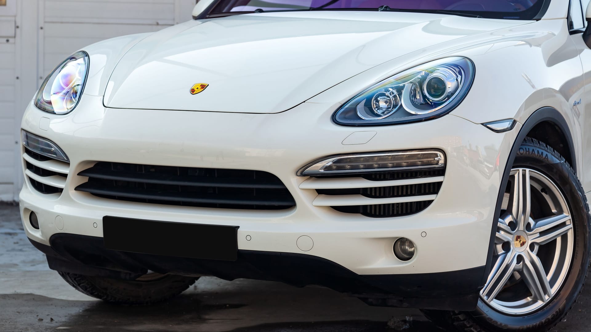 White Porsche Cayenne 958 2011 year front view in excellent condition in a parking space among other cars at sunny day