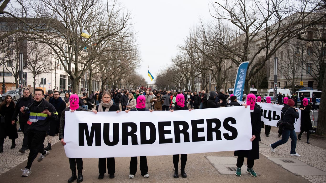 Demonstranten halten ein Transparent mit der Aufschrift "Murderers" ("Mörder") vor der russischen Botschaft in Berlin-Mitte hoch.