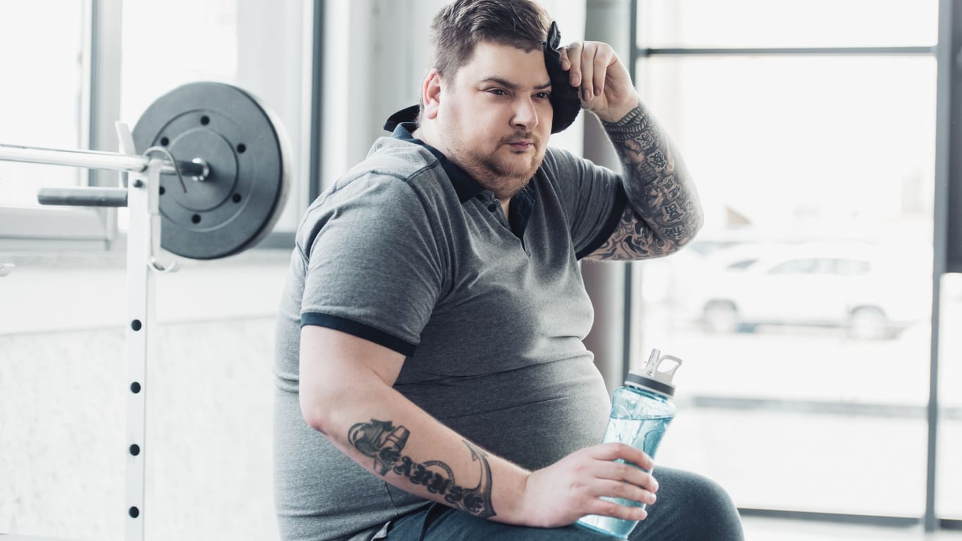 Mann mit Übergewicht und ausgeprägten Brüsten im Fitnessstudio