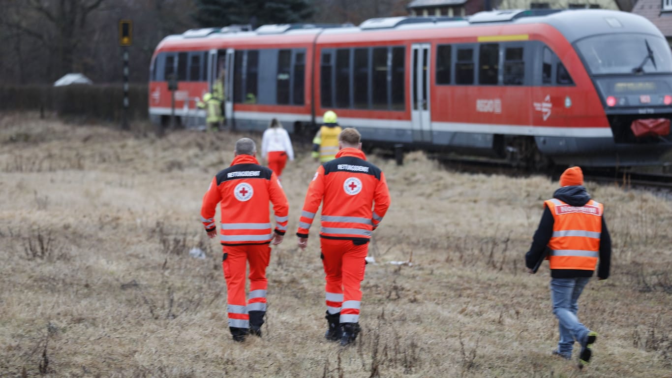 Rettungskräfte laufen zu der Regionalbahn: Dieser Zug ist am Freitagmorgen mit einem Ford kollidiert – aktuell ist noch nichts über Verletzte aus dem Zug bekannt.