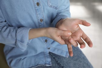 Frau mit Schnappfinger am Ringfinger: Rastet der Finger beim Beugen ein, liegt wahrscheinlich ein sogenannter Schnappfinger vor.