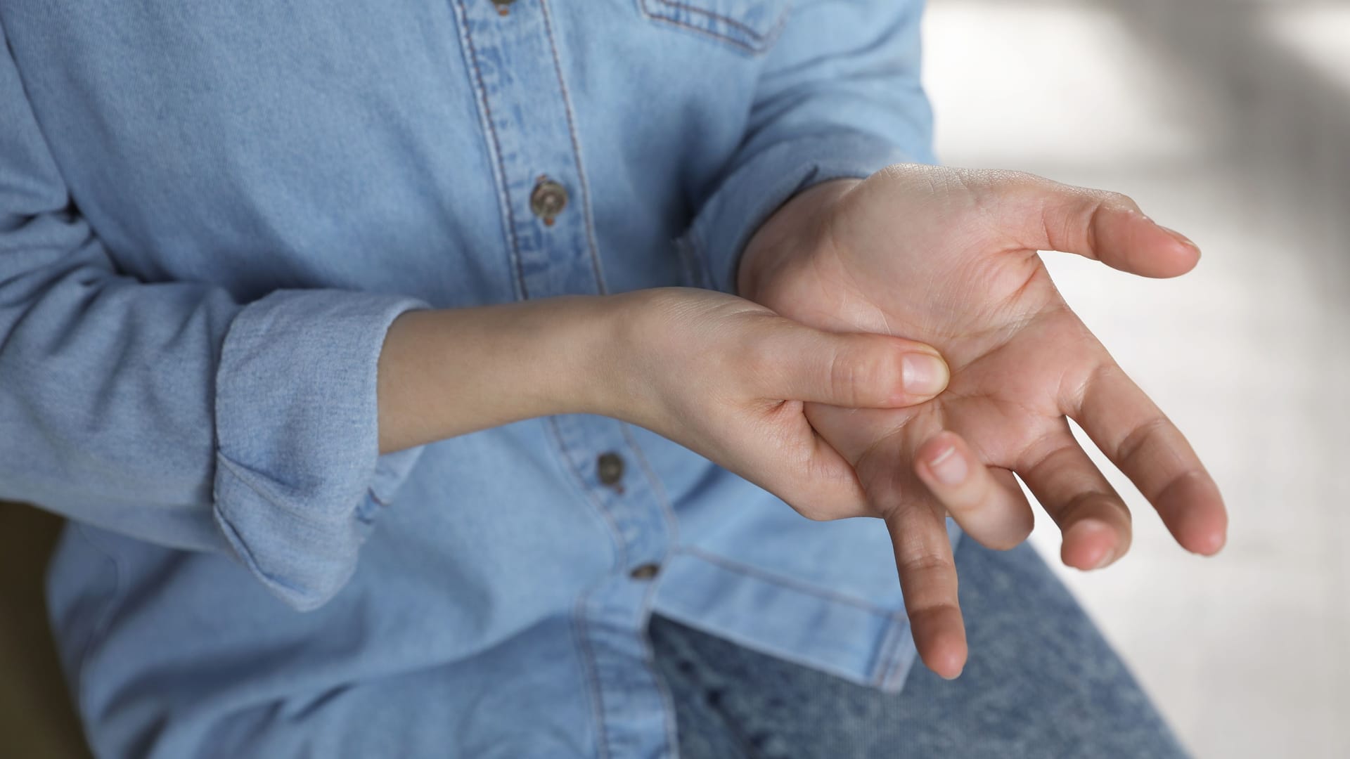 Frau mit Schnappfinger am Ringfinger: Rastet der Finger beim Beugen ein, liegt wahrscheinlich ein sogenannter Schnappfinger vor.