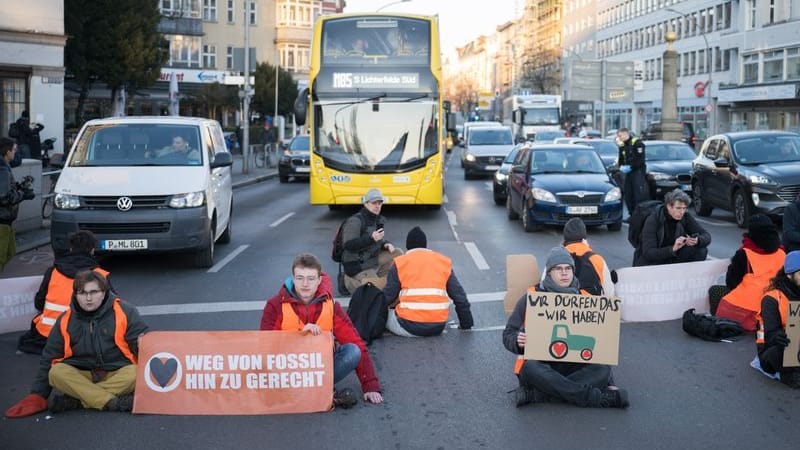 ARCHIV - Aktivisten der Letzten Generation sitzen bei einer Straßenblockade auf der Straße