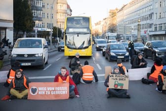 ARCHIV - Aktivisten der Letzten Generation sitzen bei einer Straßenblockade auf der Straße