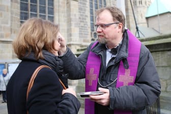Cityseelsorger Bernd Wolharn zeichnet Passanten am Essener Dom ein Aschekreuz auf die Stirn (Archivfoto).