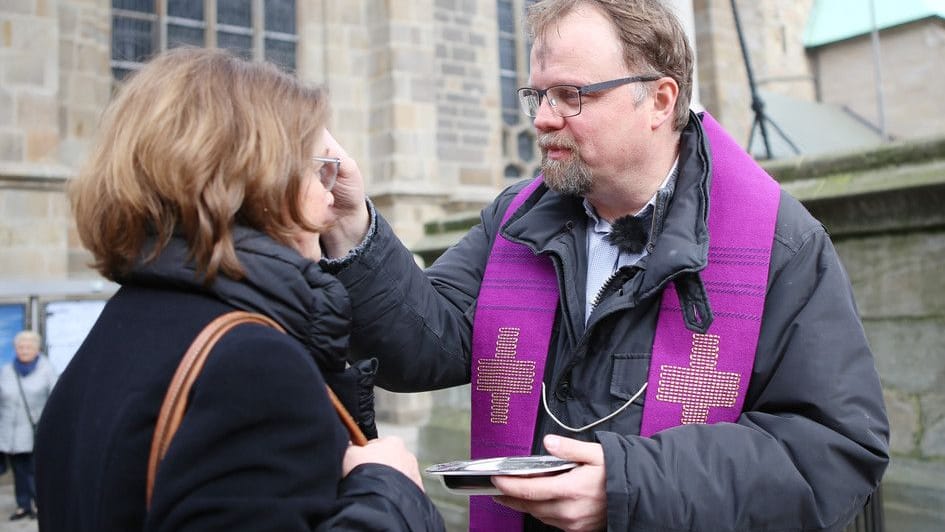 Cityseelsorger Bernd Wolharn zeichnet Passanten am Essener Dom ein Aschekreuz auf die Stirn (Archivfoto). Cityseelsorger Bernd Wolharn zeichnet Passanten am Essener Dom ein Aschekreuz auf die Stirn (Archivfoto).