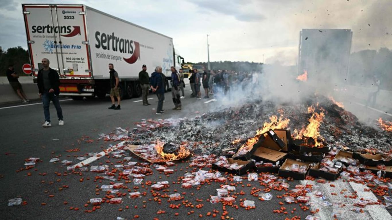 Frankreich: Protestierende Menschen stehen neben brennenden Tomaten-Paletten auf der Straße.
