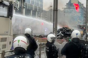 Ein Wasserwerfer der Polizei löscht brennende Reifen: In Brüssel geraten Polizei und Landwirte aneinander.