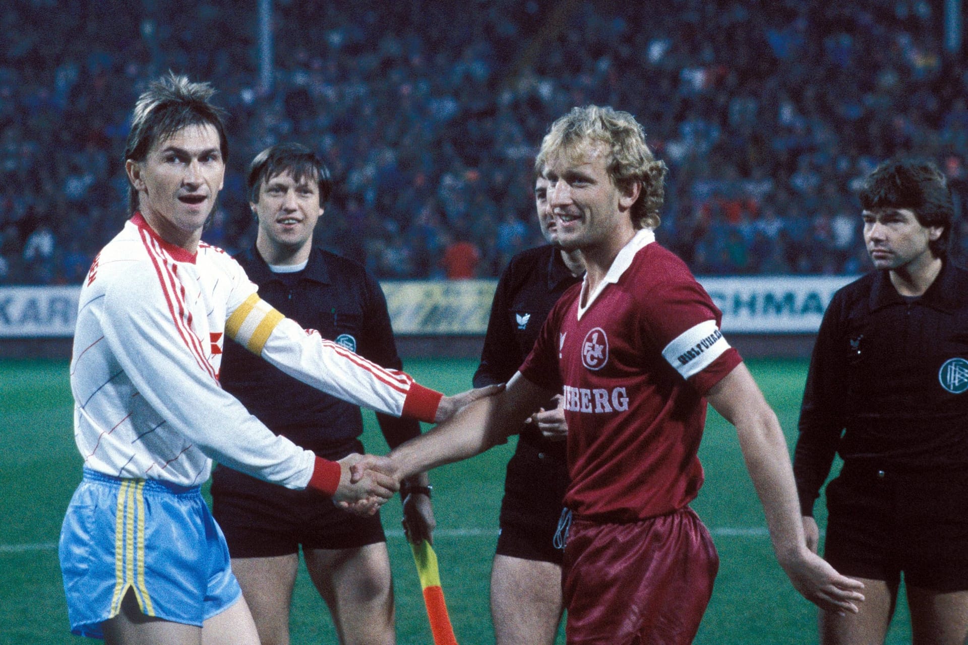 Nach einer Saison ging es eine Klasse höher und Brehme zog weiter zu Bundesligist 1. FC Kaiserslautern. Im Bild schüttelt er in der Saison 1984/85 als FCK-Kapitän die Hand von Bayerns Klaus Augenthaler (l.), mit dem er später Weltmeister werden sollte.