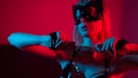 Blonde girl in a leather mask and handcuffs in the bedroom in red blue neon light. Role-playing games.