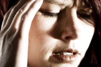 Eine Frau fasst sich an den Kopf (Symbolbild): Rücken-, Kopf- und Gelenkschmerzen gehören zu den häufigsten Arten chronischer Schmerzen.