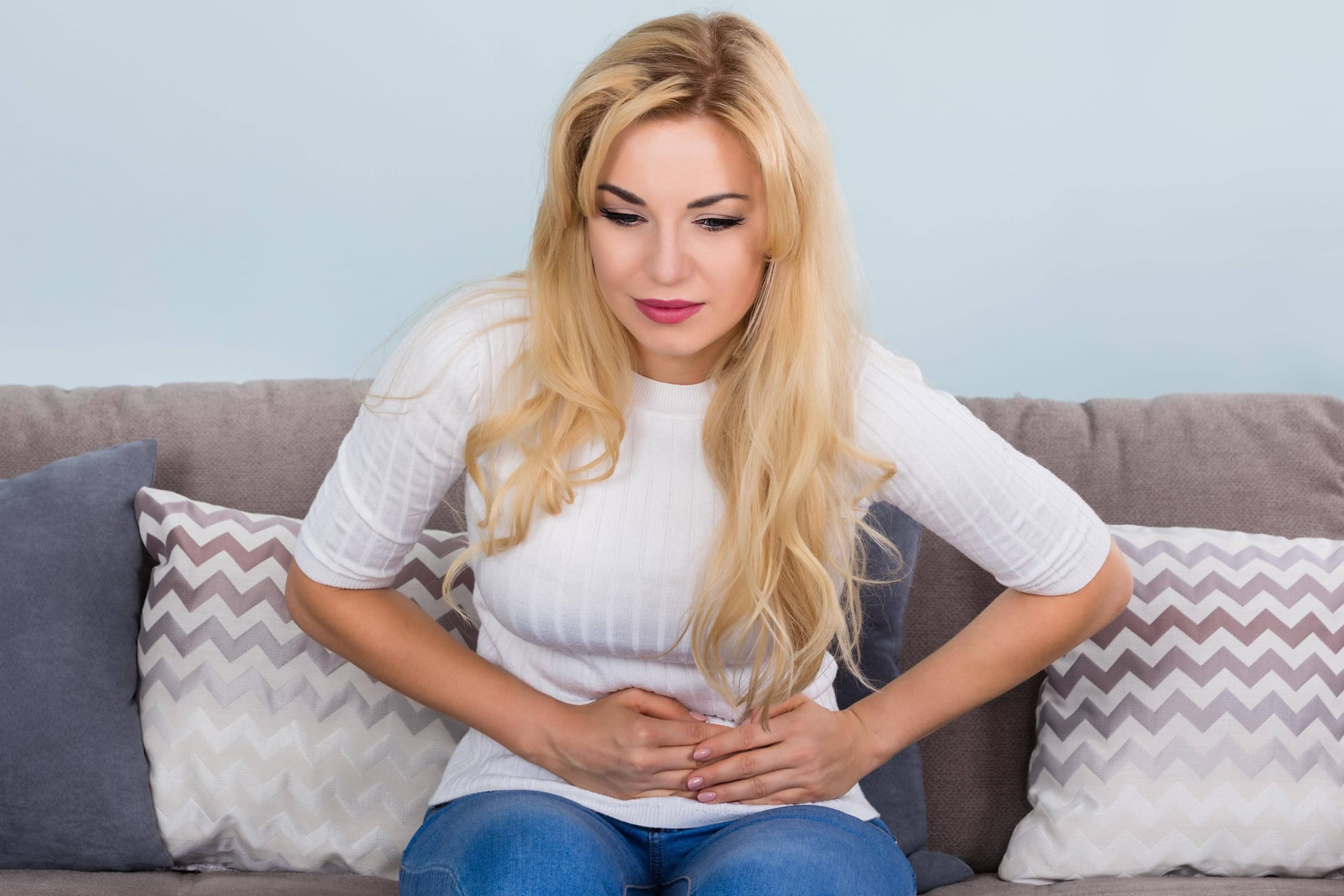 Eine Frau hält sich den Bauch (Symbolbild): Rücken-, Kopf- und Gelenkschmerzen gehören zu den häufigsten Arten chronischer Schmerzen.