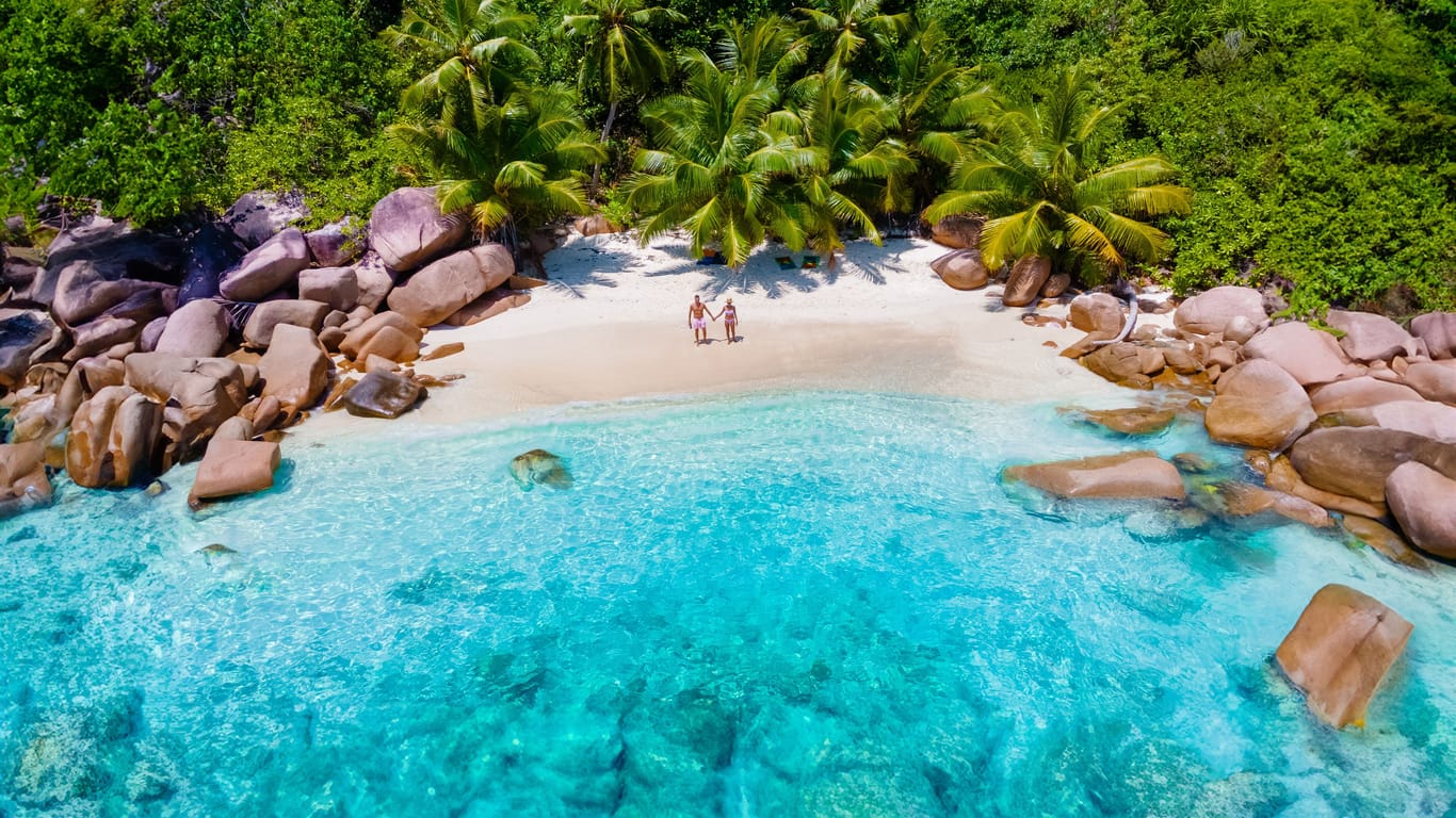 Praslin Seychelles tropical island with withe beaches and palm trees, couple men and women mid age on vacation at the Seychelles visiting the tropical beach of Anse Lazio Praslin Seychelles drone view