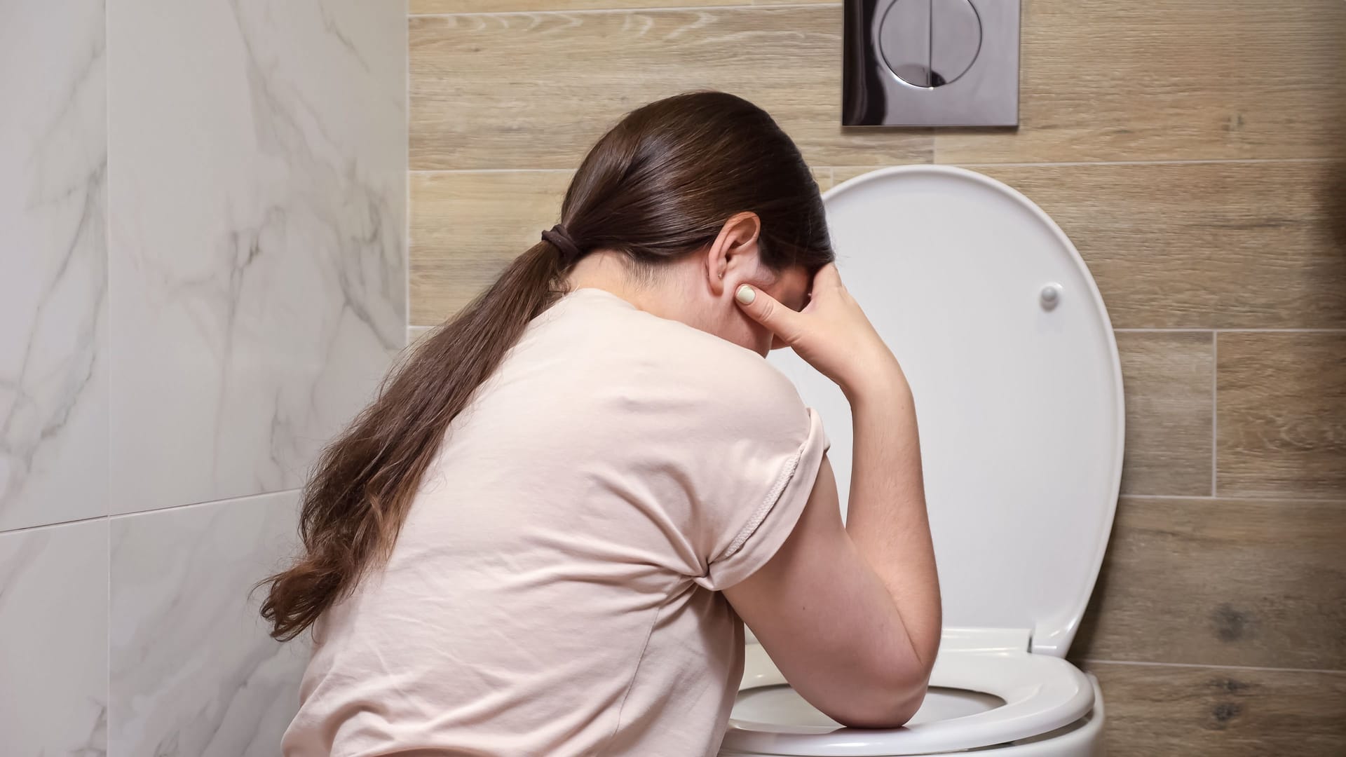 Eine Frau übergibt sich auf der Toilette