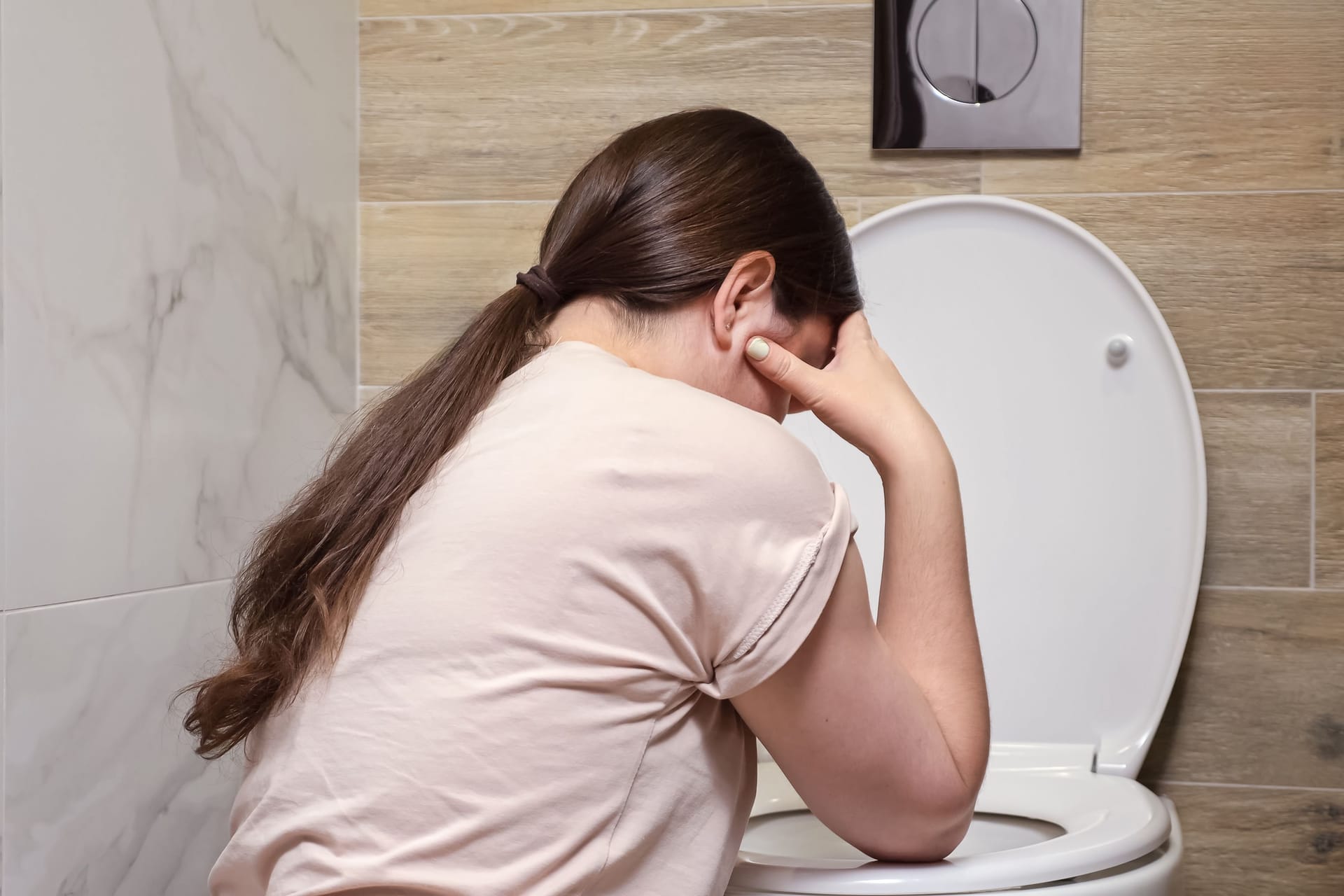 Eine Frau übergibt sich auf der Toilette