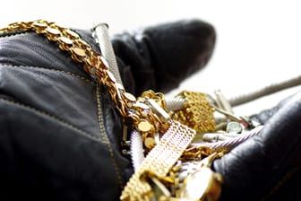 Ein Dieb hält Schmuck in der Hand (Symbolbild): Unbekannte haben ein Juweliergeschäft in Berlin-Schmargendorf überfallen.