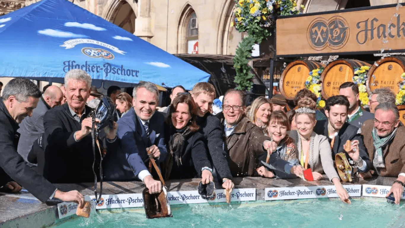 Screenshot von der Stadt München: Oberbürgermeister Reiter und andere Vertreter der Stadt ziehen ihre Geldbeutel für finanzielles Glück durch das Wasser.