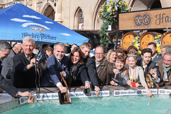 Screenshot von der Stadt München: Oberbürgermeister Reiter und andere Vertreter der Stadt ziehen ihre Geldbeutel für finanzielles Glück durch das Wasser.