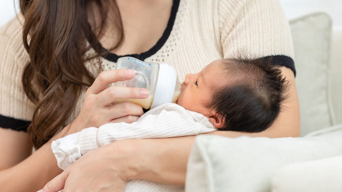 Baby wird mit Milch aus der Flasche gefüttert