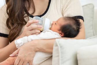 Baby wird mit Milch aus der Flasche gefüttert