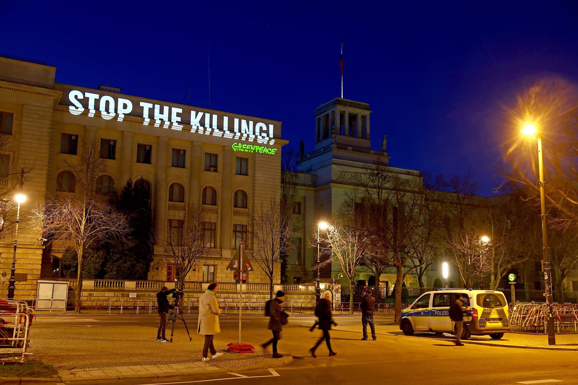 People cross a road as Greenpeace activists set up a protest projection onto the Russian embassy, marking the second anniversary of the Russian invasion of Ukraine, in Berlin, Germany February 24, 2024.