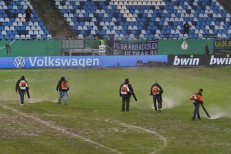 Trocknungsversuche in Saarbrücken: Starke Regenfälle bedrohen das DFB-Pokalspiel gegen Gladbach.
