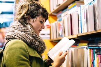 Eine Frau liest in einem Buch (Symbolbild): In Hannover muss die Stadtbibliothek sparen.