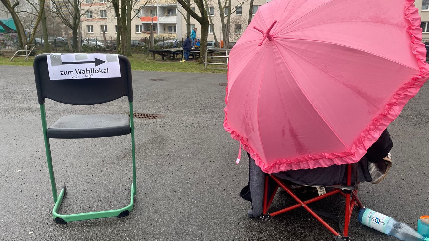 Wahlhelferin unter einem Regenschirm in Lichtenberg.