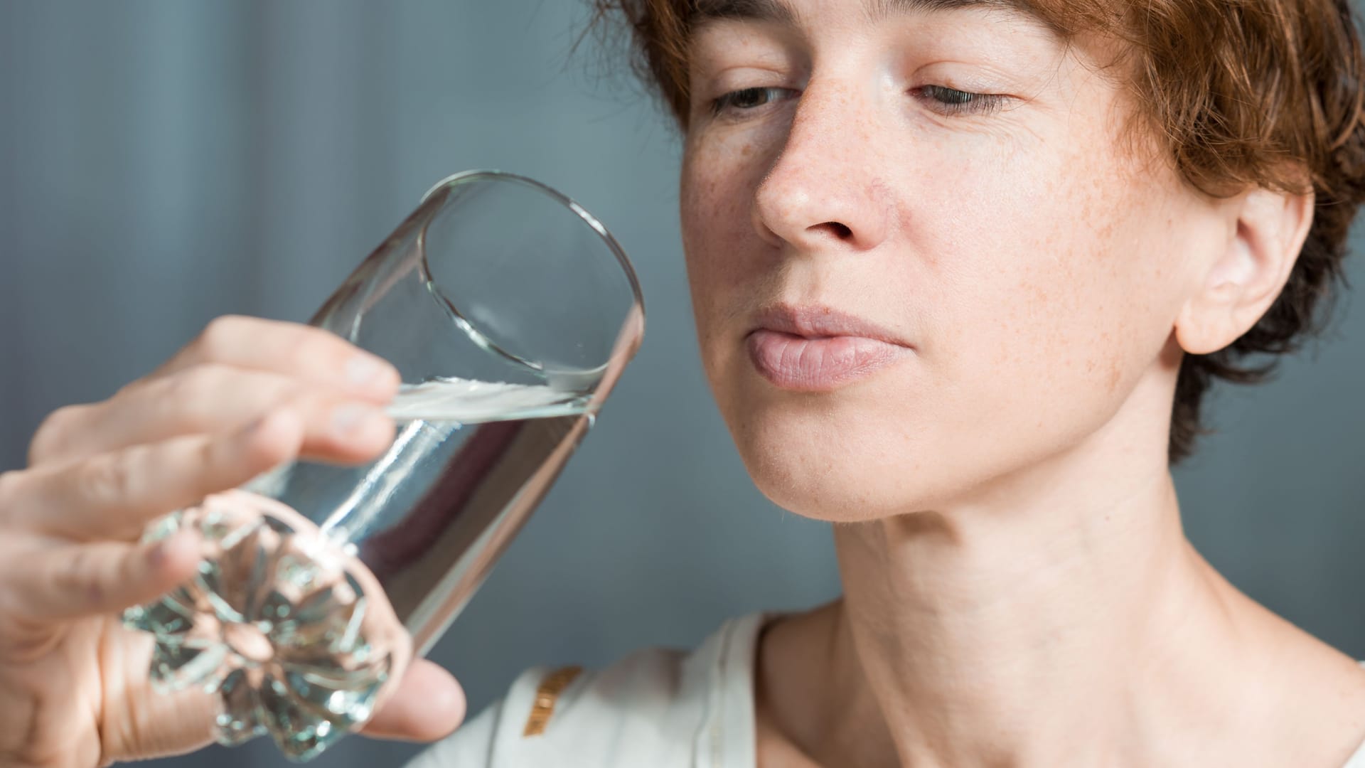 Eine Frau betrachtet ein Glas Wasser