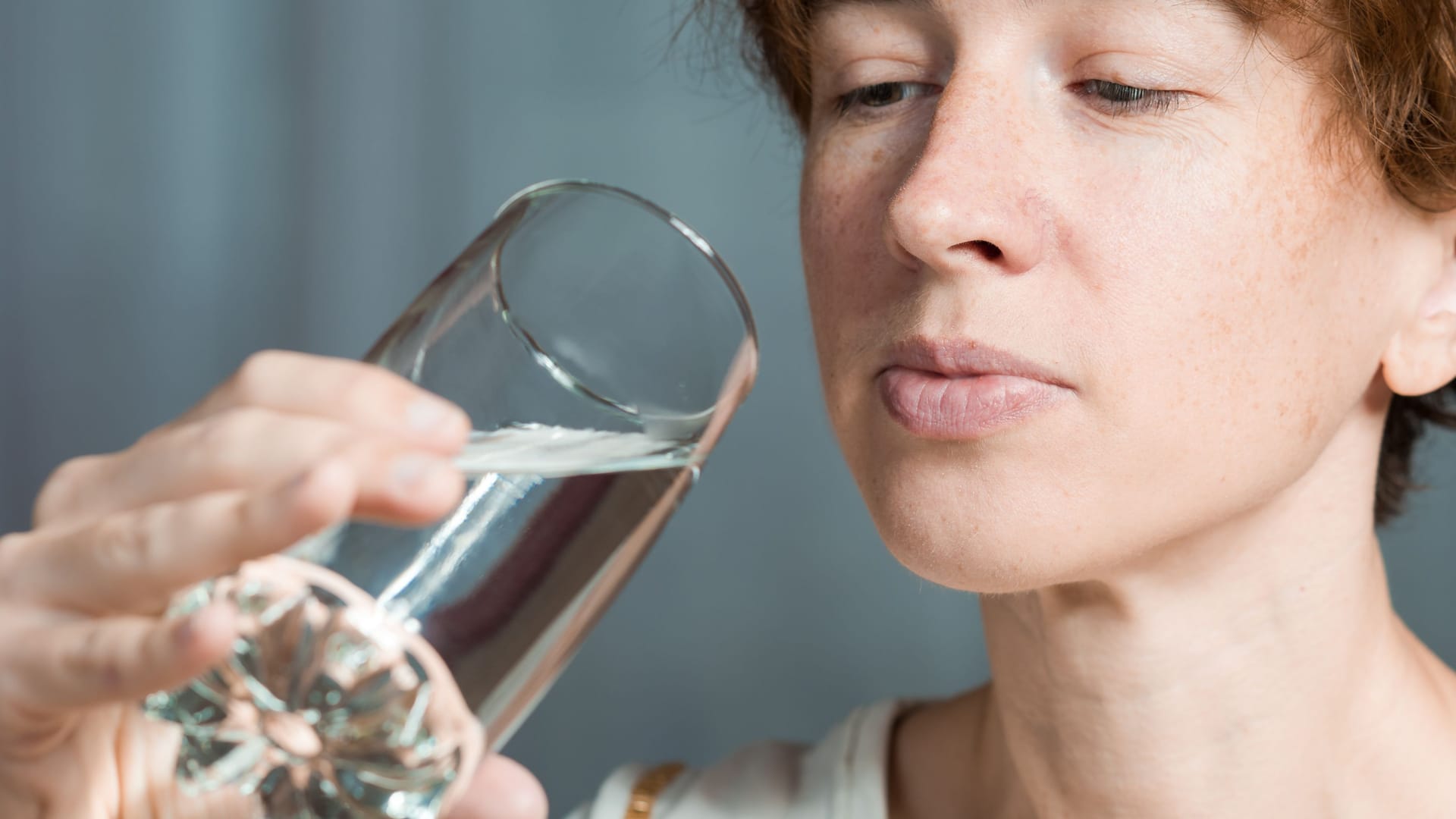 Eine Frau betrachtet ein Glas Wasser