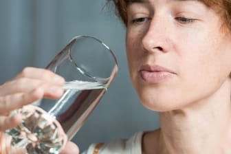 Eine Frau betrachtet ein Glas Wasser