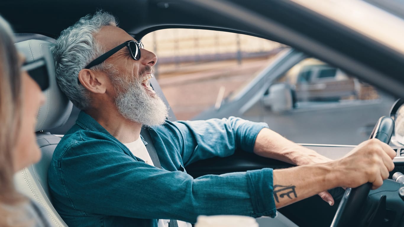 Älterer Autofahrer und Beifahrerin lachen