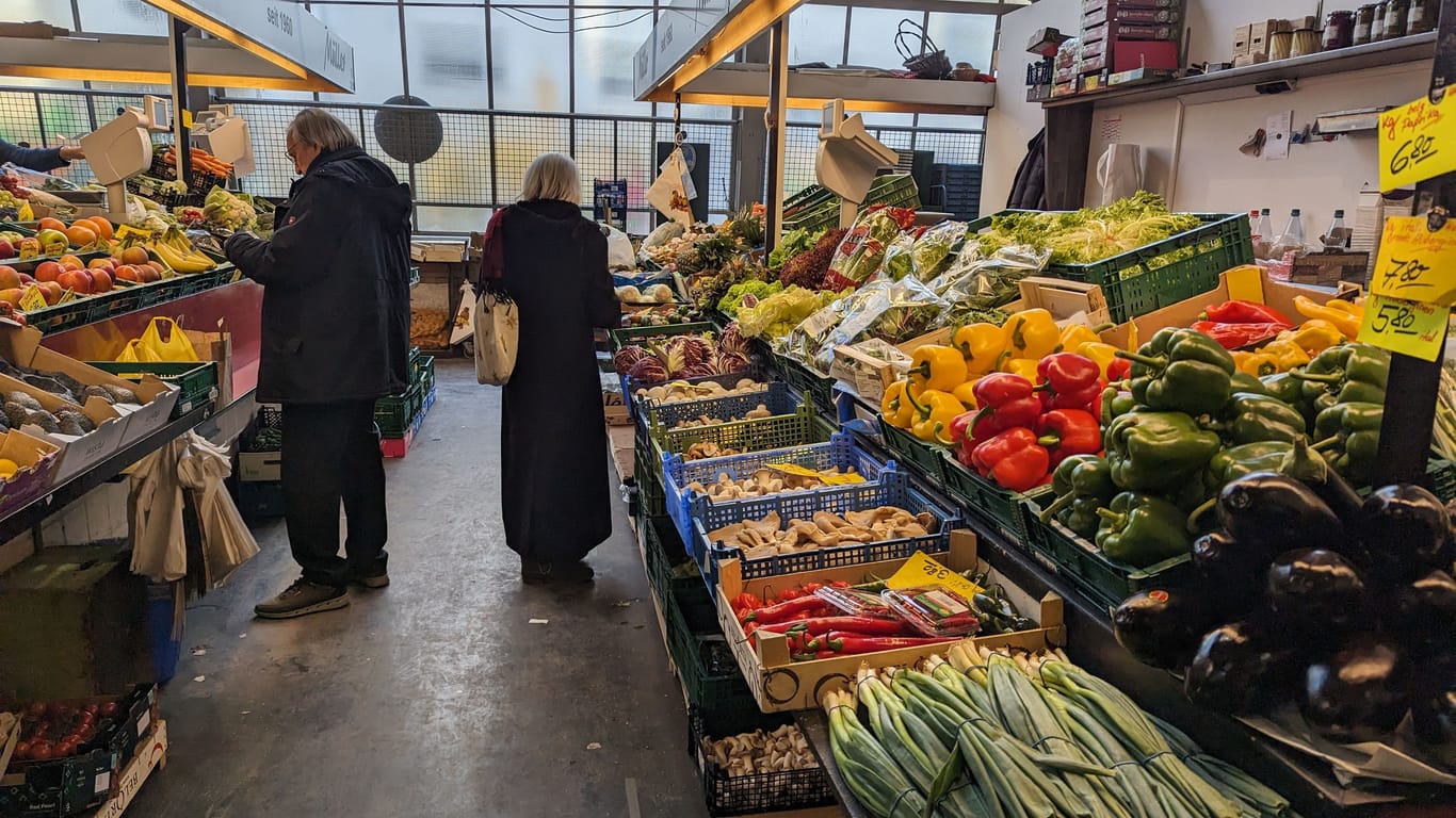 Kunden an einem Gemüsestand in der Kleinmarkthalle