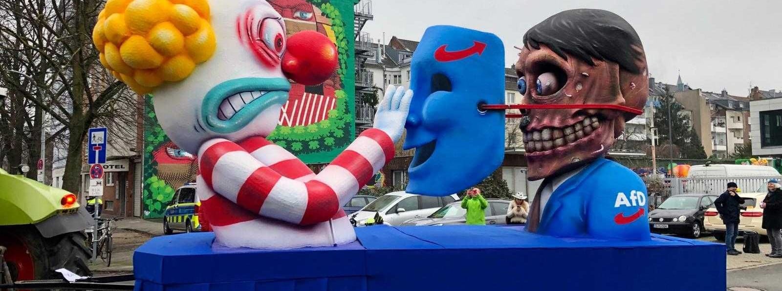 Bei der AfD fällt die Maske und die Karnevalisten entdecken dahinter mit großer Ablehnung Adolf Hitler.